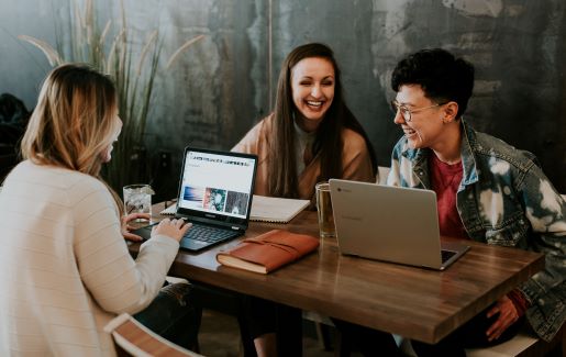 Three students working and laughing together at a table.