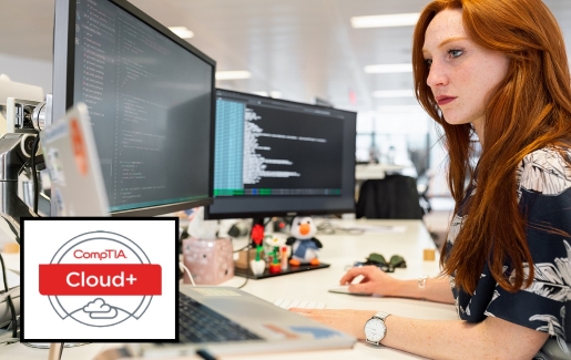 Woman at desk working on coding with 2 monitors and a laptop.