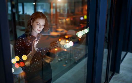 A woman at work looking at a tablet in a modern office.