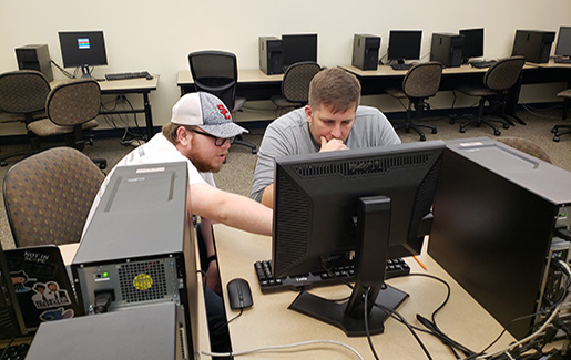 Kevin Borah and Will Duncan work together to solve a cybersecurity challenge at a workstation