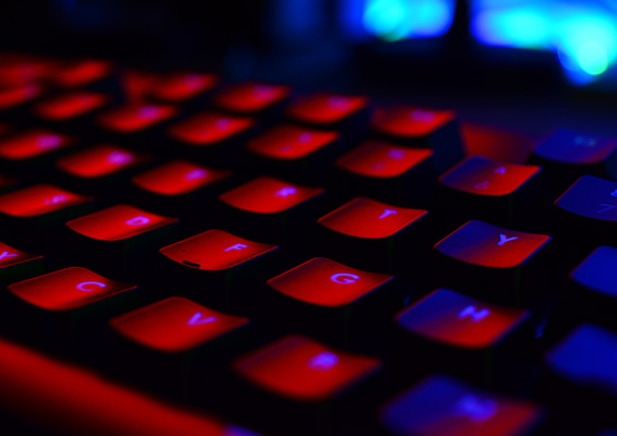 A keyboard in a dark room with red and blue reflections