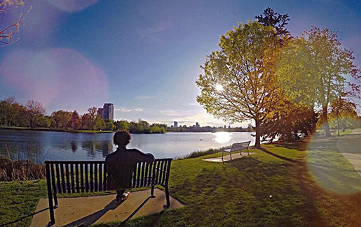 A man sits on a bench in a park in Denver