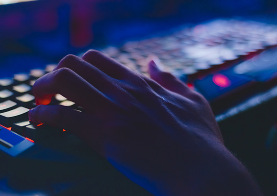 A person types on a keyboard in a dark room