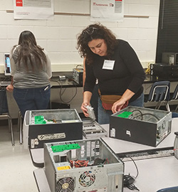 A student in the Community Education ESL Computer Maintenance Class works on installing a hard drive.