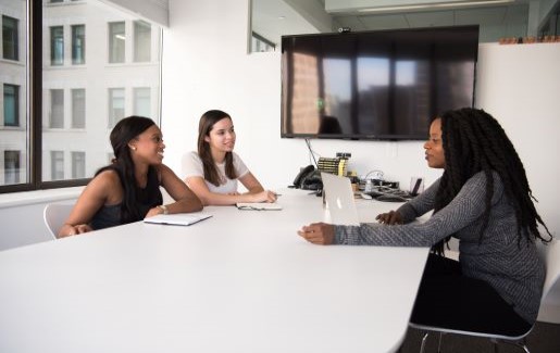 Three women at work in a conference room having a meeting.