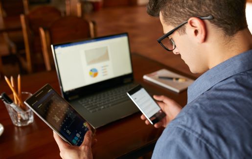 IT pro multitasking between a tablet, laptop and mobile device.