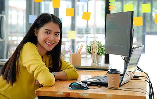 A woman who works in IT smiles while sitting at her desk at work