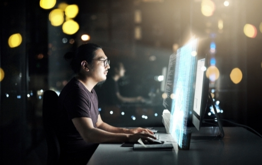 Male with glasses working in the dark on bright computer screen