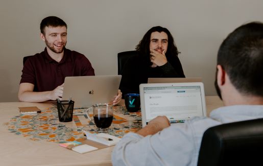 Three men working together on laptops at a table. 