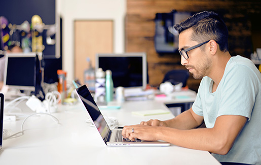 A Linux developer works on a laptop in an open office environment