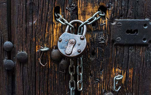 A padlock with lots of chains keeping a wooden door secure