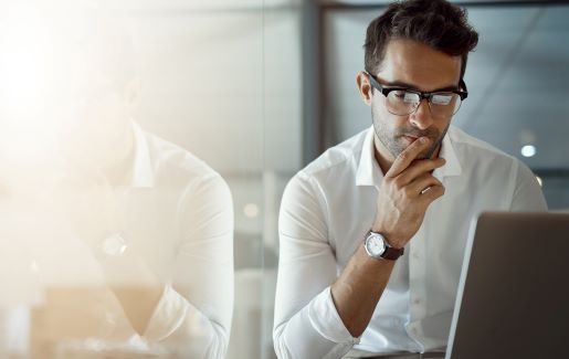 IT pro with glasses looking at laptop pensively and wondering about ransomware