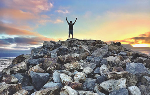 A man stands atop rocks overlooking the Pacific Ocean in San Diego