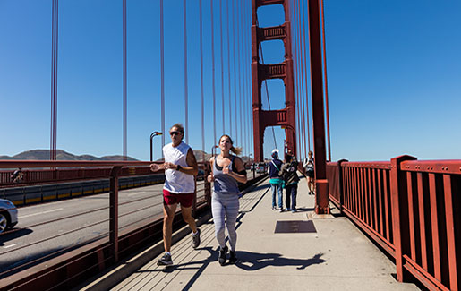 A man and women run across the Golden Gate Bridge in San Francisco