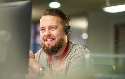 Male technical support with beard smiling in front of computer