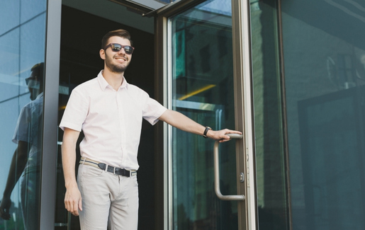 Male with sunglasses walking out of a building