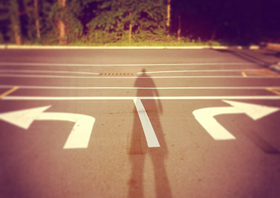 The shadow of a person at an intersection with a right turn lane and a left turn lane