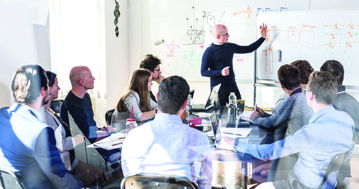 People in a meeting looking at a board