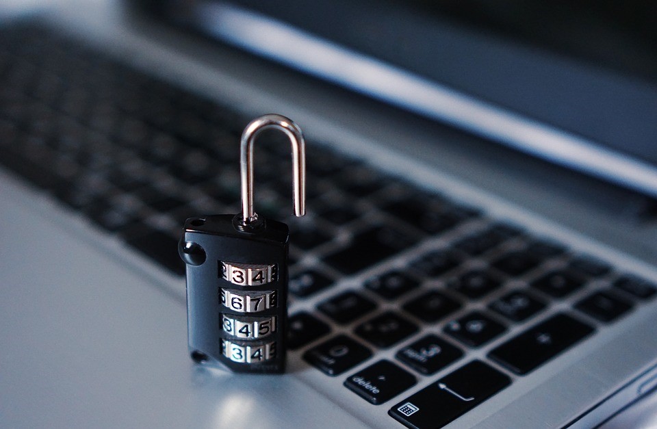 An open padlock sits on top of a silver laptop computer